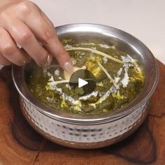 a person is stirring some food in a pot on a wooden board with a spoon