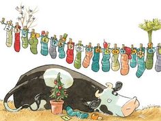 a cow laying on the ground next to a christmas tree with stockings hanging from it