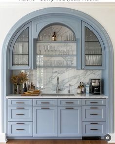 a kitchen with blue cabinets and marble counter tops in an arch - shaped niche above the sink