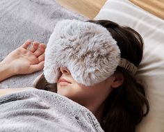 a woman laying on top of a bed wearing a blindfold