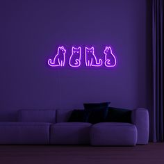 a purple neon sign with three cats on it in front of a couch and window