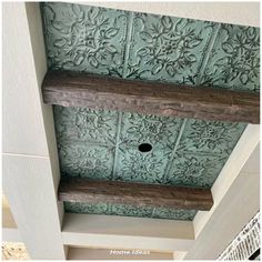 the ceiling is painted green and has wooden shelves above it with decorative designs on them