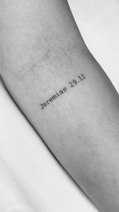 a person with a small tattoo on their arm that reads jeremias 21 11