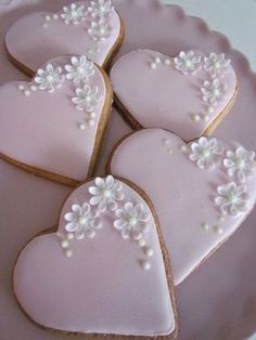 heart shaped cookies decorated with white flowers on a pink plate