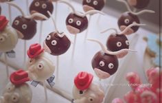 there are many cake pops decorated like animals with hats on them, and one is wearing a red hat