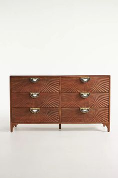 a wooden dresser with four drawers and three bowls on it's front legs, against a white background