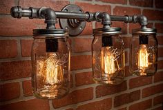 three mason jar lights hanging from a brick wall