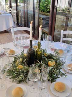 the table is set with wine glasses, plates and candles for an elegant dinner party