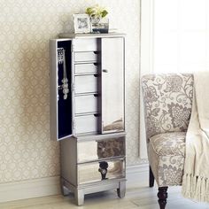 a mirrored cabinet with drawers in a living room next to a chair and wallpaper