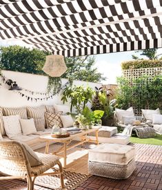 an outdoor living area with black and white striped awnings over the couches