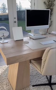 an office desk with a computer, keyboard and mouse on it in front of a window