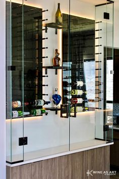 a wine cellar with glass walls and shelves filled with bottles on the wall, next to a counter