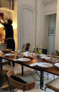 a person standing over a table filled with plates and bowls on top of wooden tables