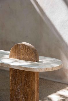 a marble bench sitting in front of a white wall and shadows on the ground behind it