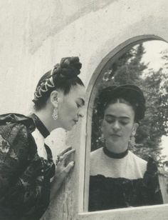 an old photo of two women looking in the mirror