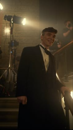 a man in a tuxedo is standing on the stairs and smiling at the camera