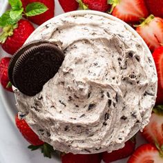 an oreo cookie on top of a white plate with strawberries and chocolate chips