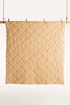 a tan quilt hanging from a clothes line