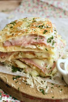 a stack of food sitting on top of a wooden cutting board next to a cup