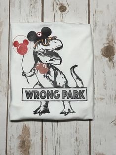 a t - shirt with an image of a dinosaur holding a balloon and the words wrong park printed on it