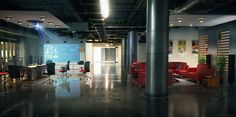 an empty office with red chairs and desks on the floor, in front of a projector screen