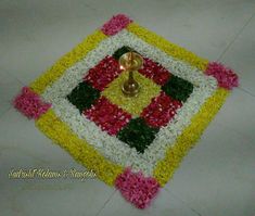 a decorated floor with flowers and a candle in the center on it, surrounded by white tiles