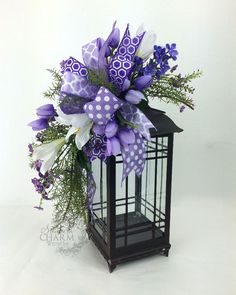 a purple and white flower arrangement in a black metal lantern with polka dots on it