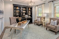 a living room filled with furniture and a chandelier above a glass top table