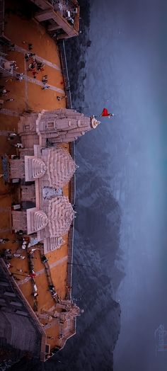 an aerial view of a castle in the middle of water with people standing around it