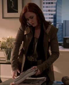 a woman is talking on the phone while standing in front of a stack of papers