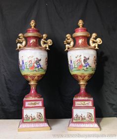 two vases sitting on top of each other with gold trimming and painted designs