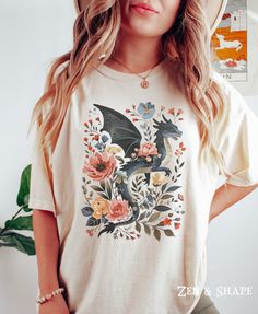 Retro Dragon Floral Comfort Colors Shirt, Cottagecore Dragon T-Shirt, Cute Black Dragon Tee, Dragon Anime TShirt, Gift For Dragon Lover PLEASE SIZE UP FOR AN OVERSIZED FIT If you are looking for an oversized "T-shirt Dress" look, we recommend sizing up 2 sizes. Comfort Colors introduces its garment-dyed t-shirt; a fully customizable tee made 100% with ring-spun cotton.  The soft-washed, garment-dyed fabric brings extra coziness to your wardrobe while the relaxed fit makes it an excellent daily c Fandom Short Sleeve Top With Front Print, Fandom Short Sleeve Top With Screen Print, Fandom Graphic Print Short Sleeve Tops, Cotton Fandom Short Sleeve Tops, Fandom Crew Neck Top With Front Print, Fandom Crew Neck Top With Sublimation Print, Fandom Sublimation Print Short Sleeve T-shirt, Short Sleeve Sublimation Print Fandom T-shirt, Fandom Crew Neck T-shirt With Sublimation Print