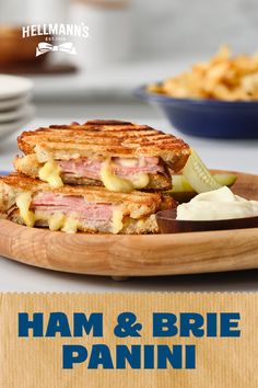 ham and brie panini with pickles on a wooden platter next to french fries