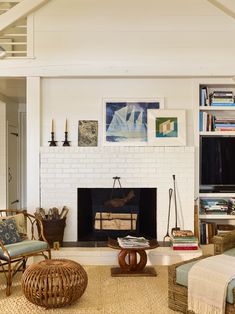 a living room filled with furniture and a fire place in front of a white brick fireplace