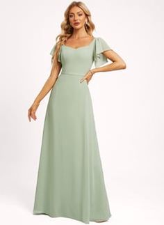 a woman in a long green dress posing for the camera with her hands on her hips