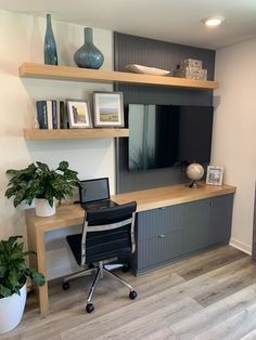 a desk with a laptop computer on top of it next to a plant and bookshelf