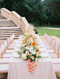 a long table with flowers and plates on it