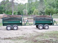 two large green trailers filled with dirt and grass