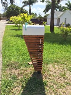 a mailbox sitting on the side of a grass covered field next to a house