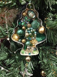 a christmas ornament hanging from a tree with green and gold ornaments on it