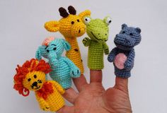 small crocheted animal finger puppets are held in the palm of a person's hand