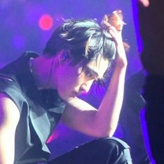 a woman sitting on top of a stage with her hand in her hair and looking down