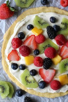 a fruit pizza with whipped cream and fresh berries on the top is ready to be eaten