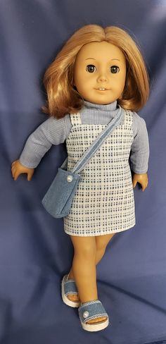 a doll with blonde hair wearing a blue dress and slippers, standing on a blue background