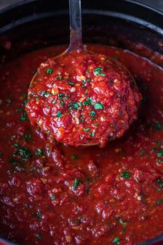 a ladle full of homemade red marinara sauce in a slow cooker with the title