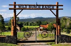 the entrance to wild bunch ranch is surrounded by stone walls and an iron gate with wheels on it