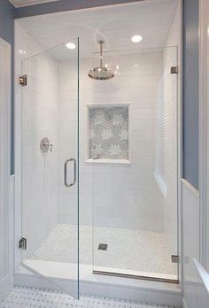 a walk in shower sitting next to a white tiled wall and floor with a glass door