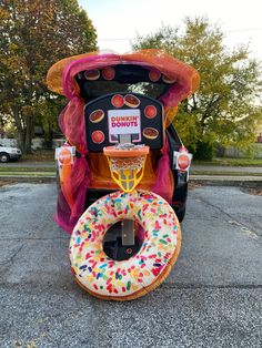 an inflatable donut sits on the ground next to a basketball hoop that is shaped like a car