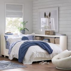 a bedroom with white walls and wood flooring has a blue blanket on the bed