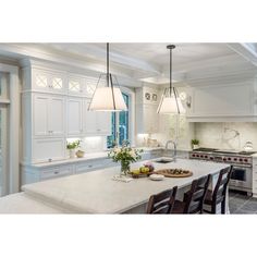 a large kitchen with white cabinets and marble counter tops, along with an island in the middle